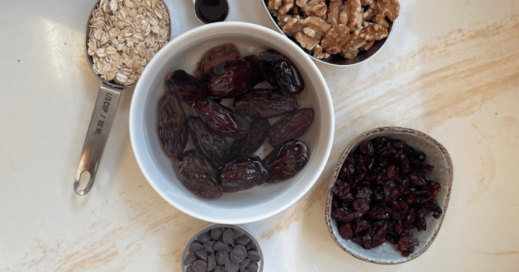 A photo of the ingredients for the chocolate cranberry walnut energy balls recipe, including walnuts, dried cranberries, chocolate chips, dates, oats, and vanilla extract.